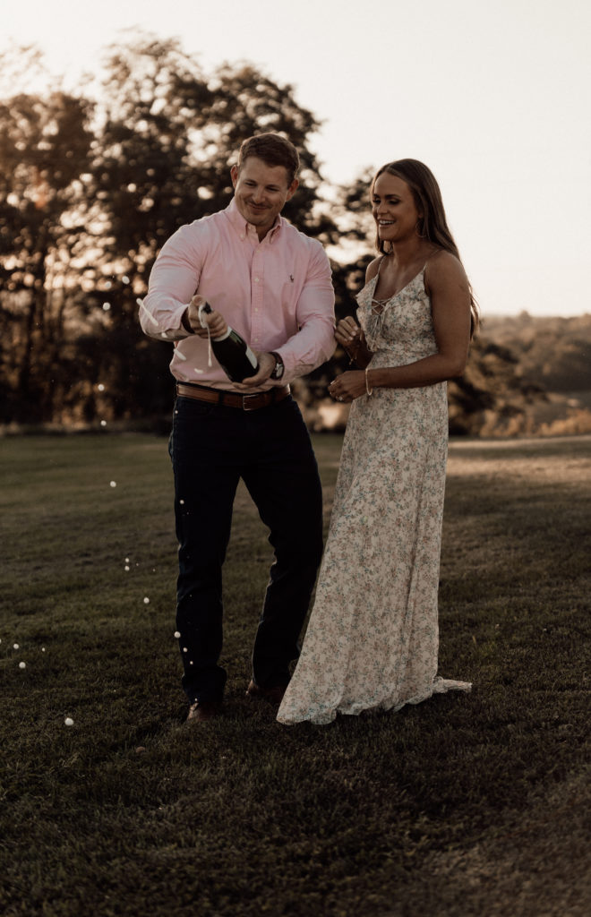 Man and woman holding champagne bottle that is bursting